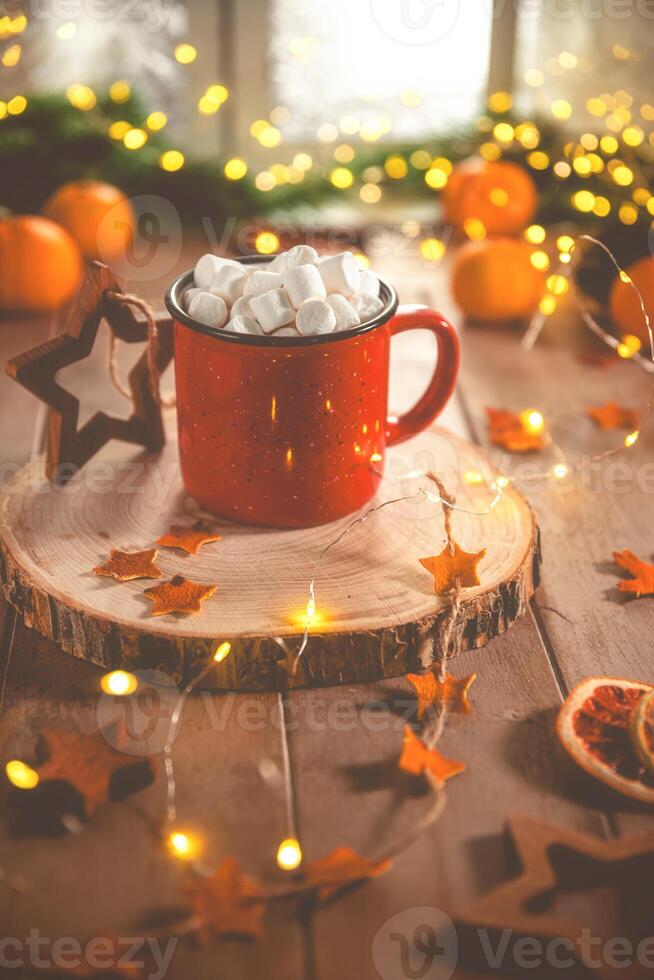 Cute cozy winter composition. red mug, marshmallows, oranges and Christmas lights. photo