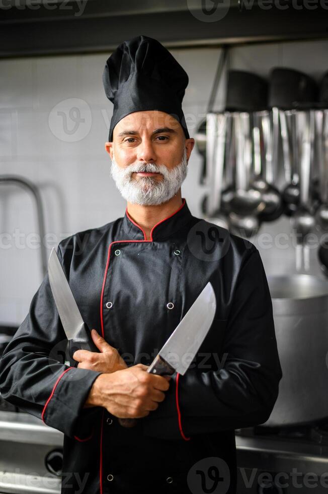 Confident chef posing with knives in kitchen photo
