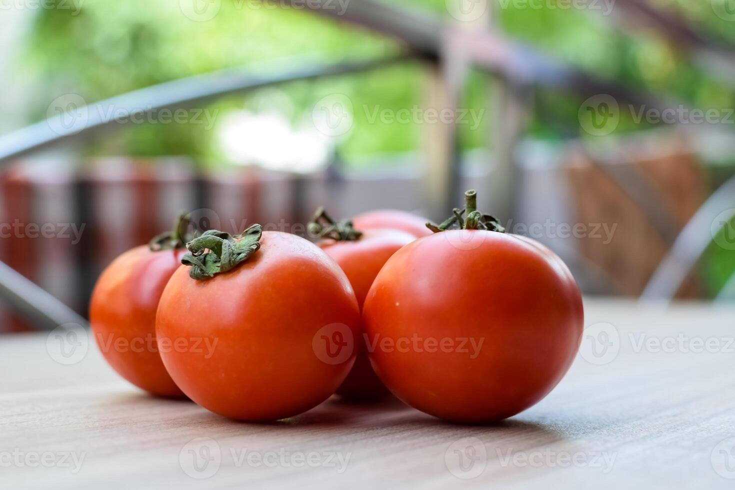 Red tomato on plain wooden table, essential vegetables for all essential foods, view of unpeeled vegetables with plain background photo