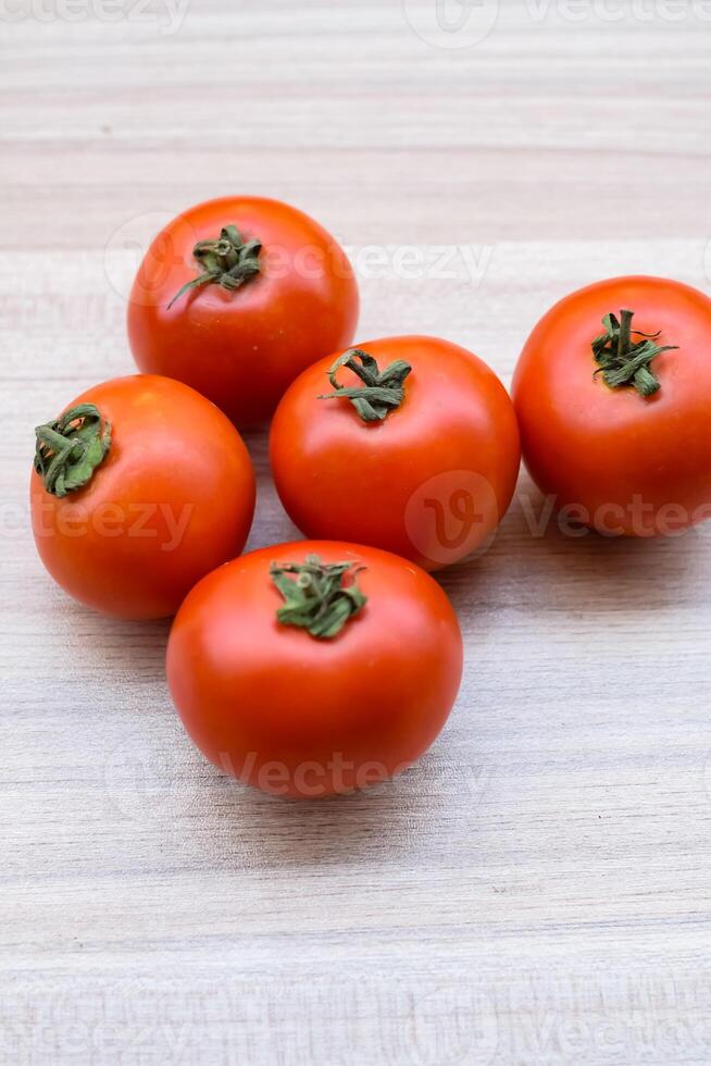 Red tomato on plain wooden table, essential vegetables for all essential foods, view of unpeeled vegetables with plain background photo