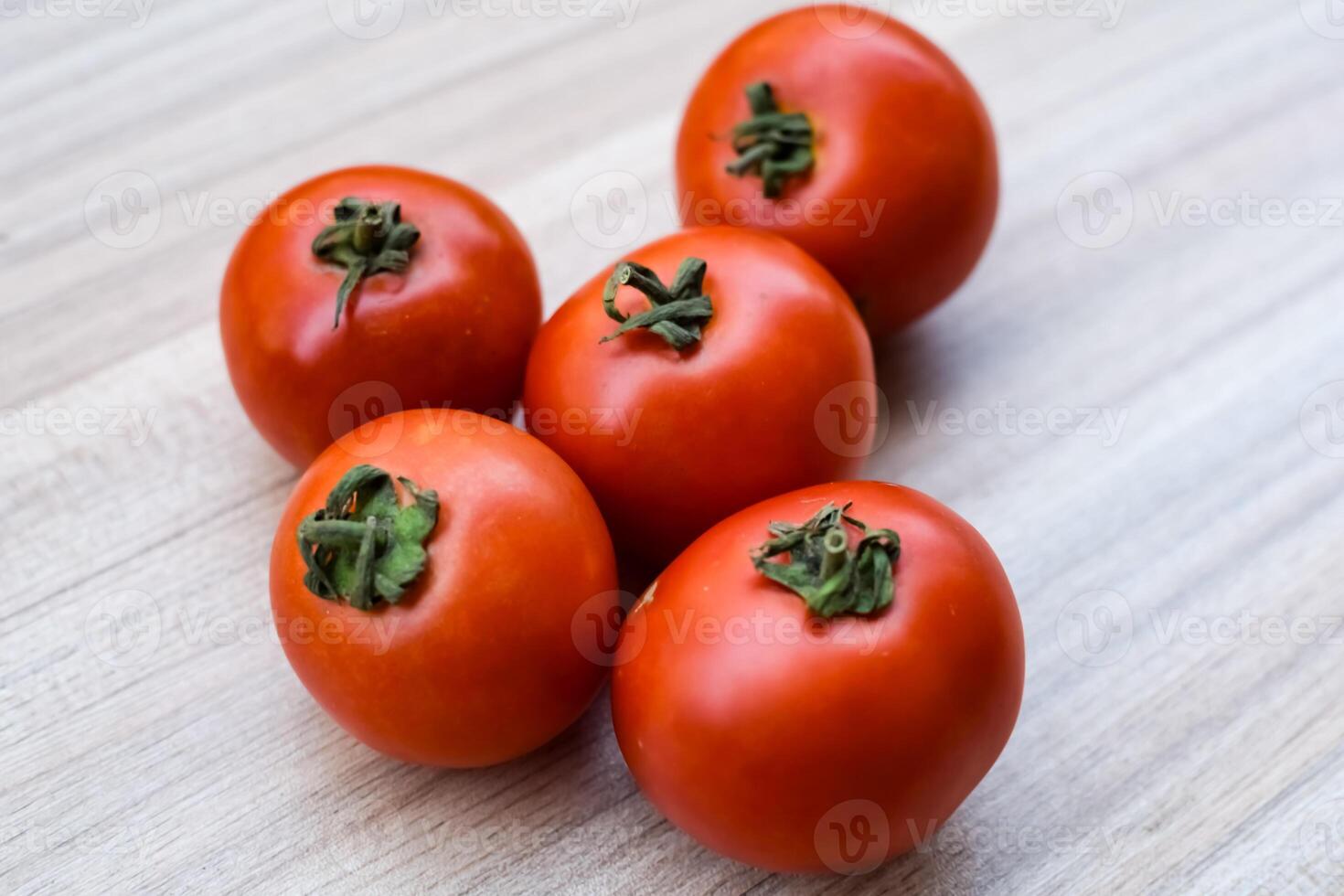 Red tomato on plain wooden table, essential vegetables for all essential foods, view of unpeeled vegetables with plain background photo