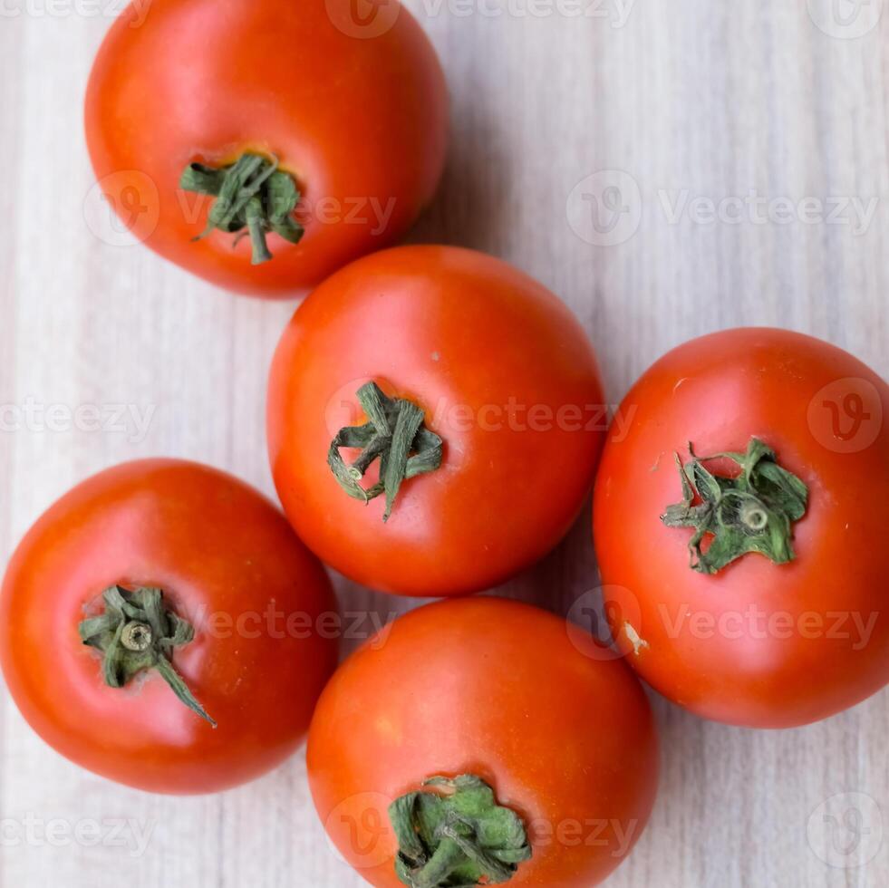 Red tomato on plain wooden table, essential vegetables for all essential foods, view of unpeeled vegetables with plain background photo