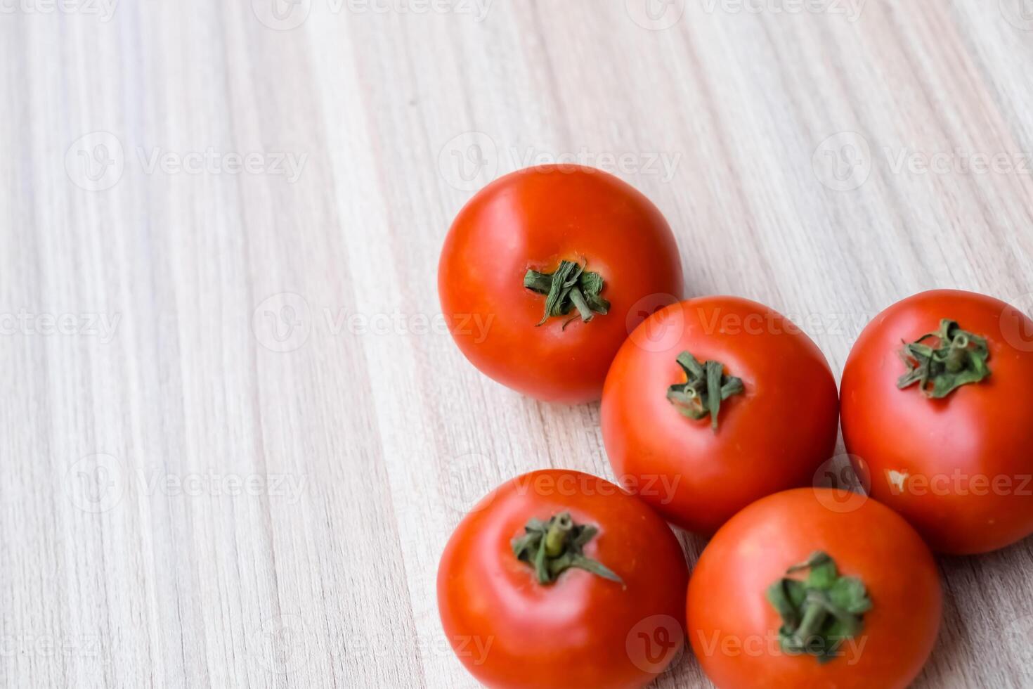 Red tomato on plain wooden table, essential vegetables for all essential foods, view of unpeeled vegetables with plain background photo