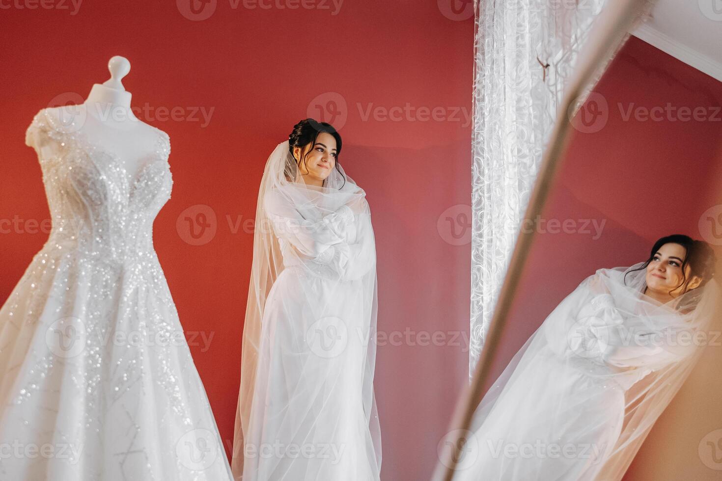 portrait of a luxurious bride in boudoir style near a mirror with reflection. Preparing the bride for the wedding in the morning in a white robe. photo