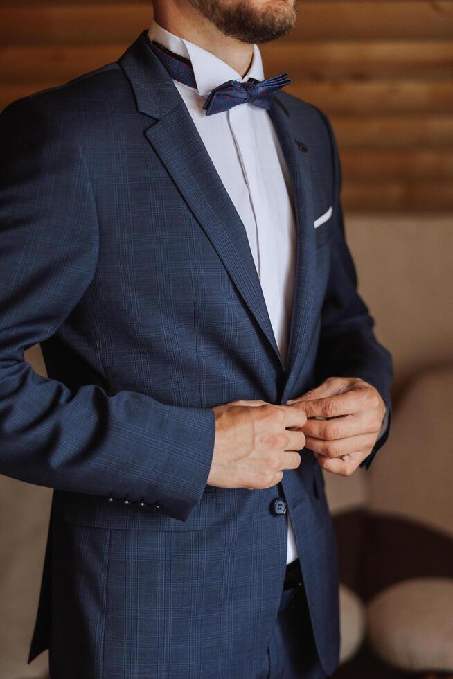 el hombre sujeta el botones en su chaqueta. el novio es preparando para el Boda ceremonia. detallado de cerca foto de manos