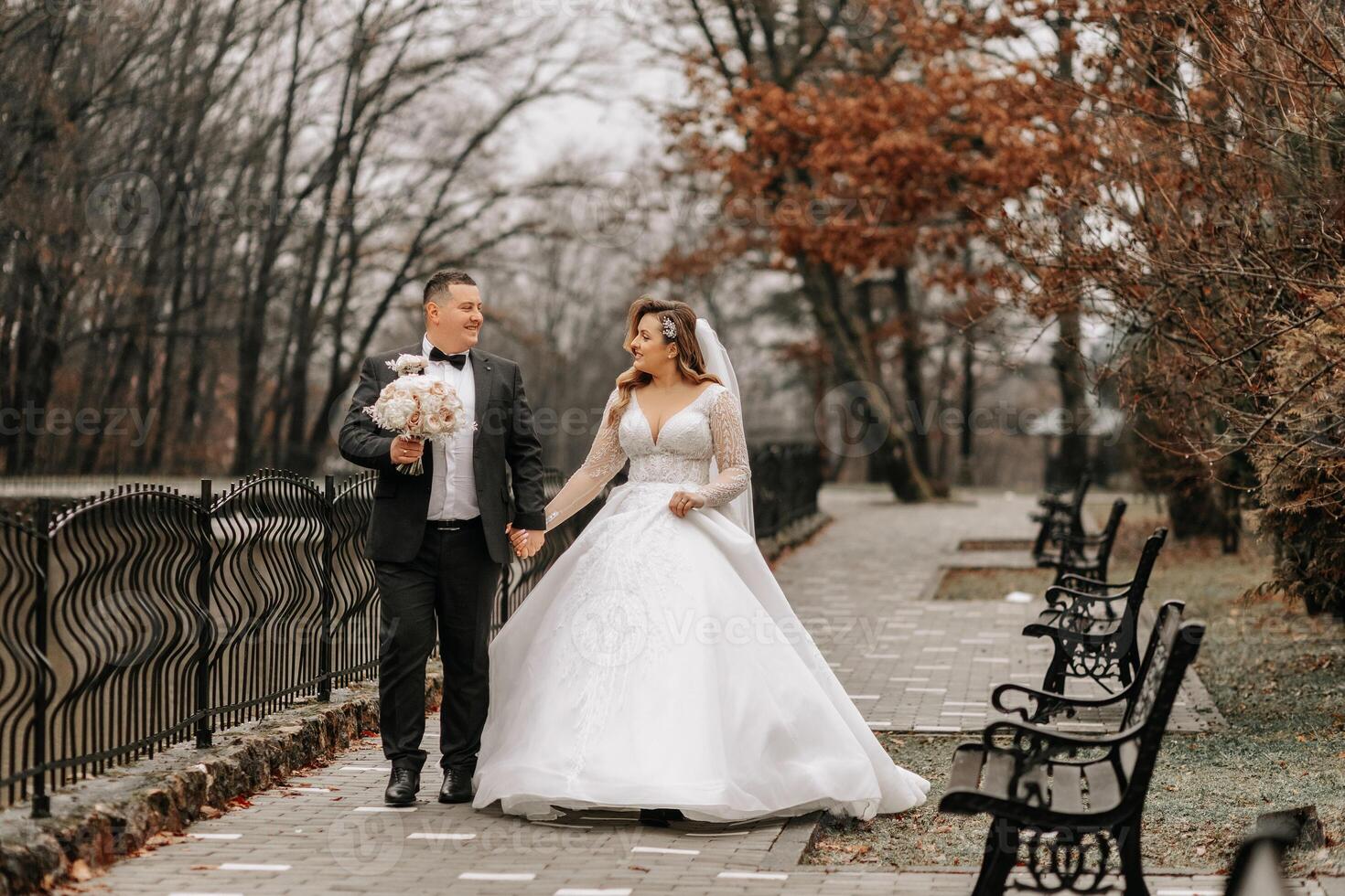 el novia y novio son caminando cerca el hotel y posando, contento y disfrutando el día, participación manos. un largo tren en el vestido. invierno Boda foto