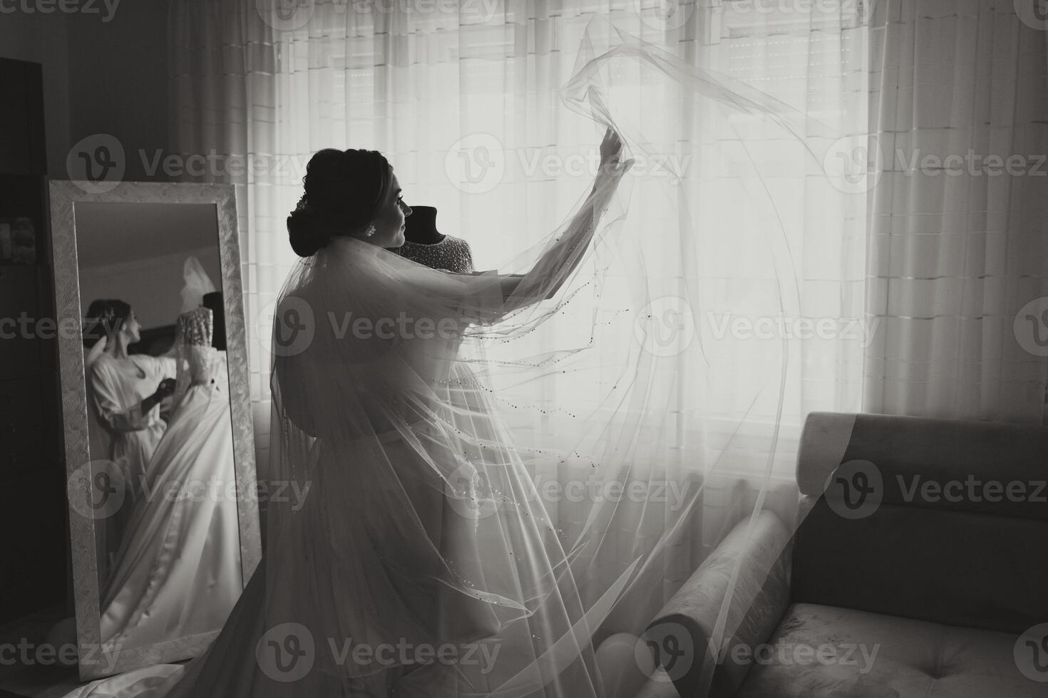 portrait of a luxurious bride in boudoir style near a mirror with reflection. Preparing the bride for the wedding in the morning in a white robe. photo