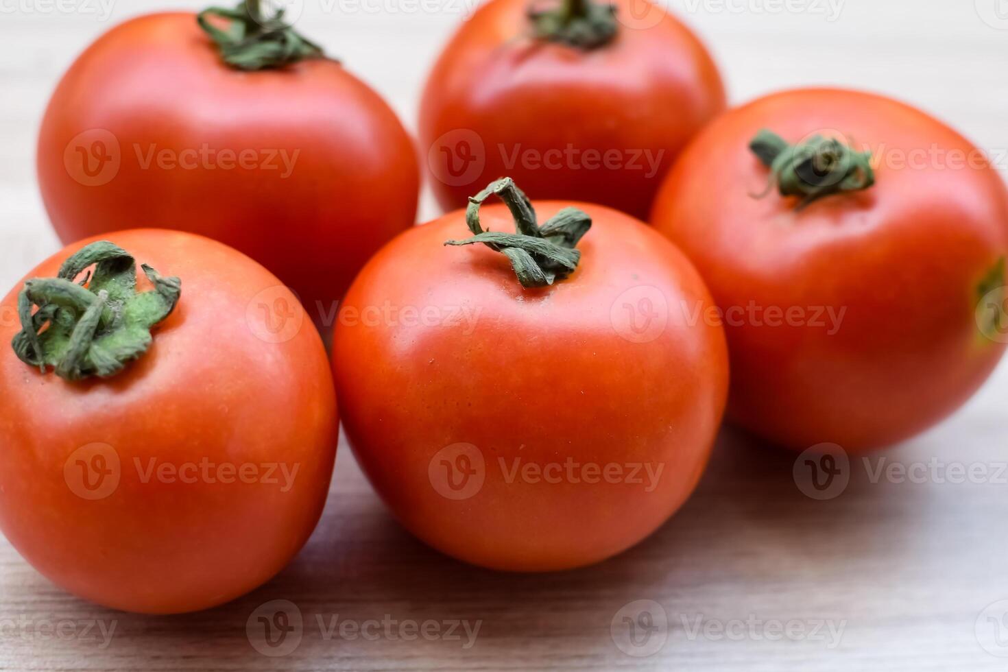 Red tomato on plain wooden table, essential vegetables for all essential foods, view of unpeeled vegetables with plain background photo