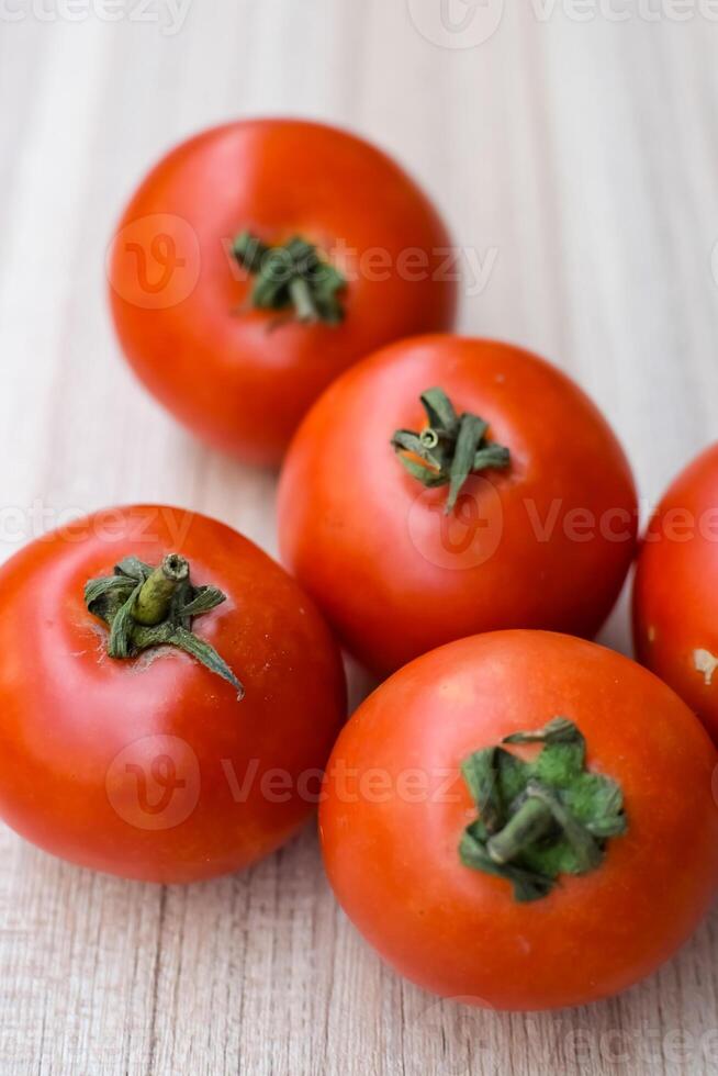 Red tomato on plain wooden table, essential vegetables for all essential foods, view of unpeeled vegetables with plain background photo