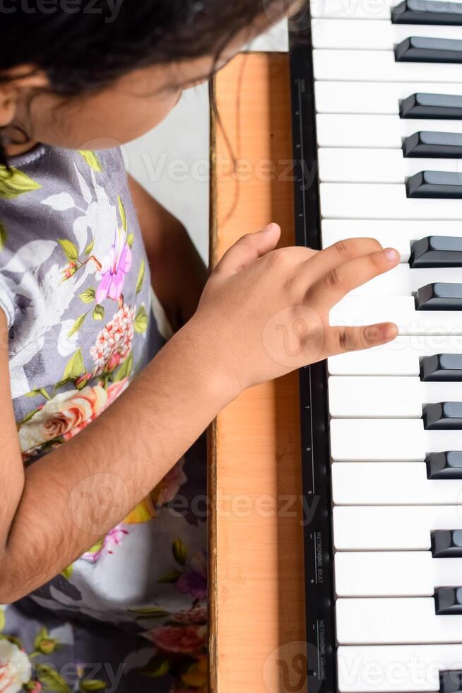 Asian cute girl playing the synthesizer or piano. Cute little kid learning how to play piano. Child's hands on the keyboard indoor. photo