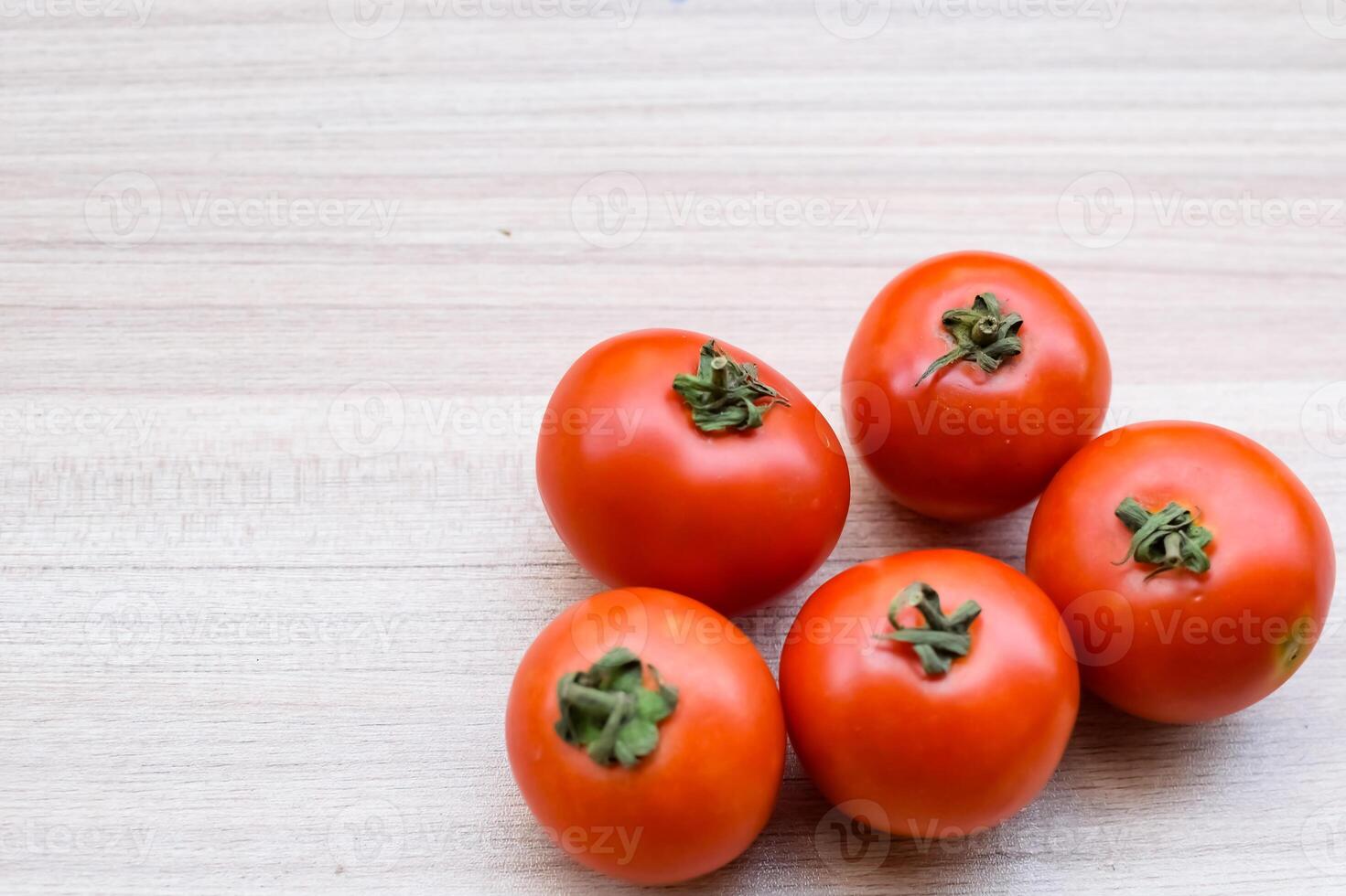 Red tomato on plain wooden table, essential vegetables for all essential foods, view of unpeeled vegetables with plain background photo
