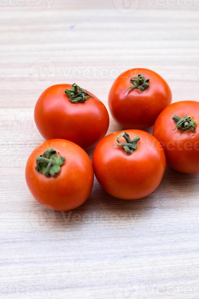 Red tomato on plain wooden table, essential vegetables for all essential foods, view of unpeeled vegetables with plain background photo