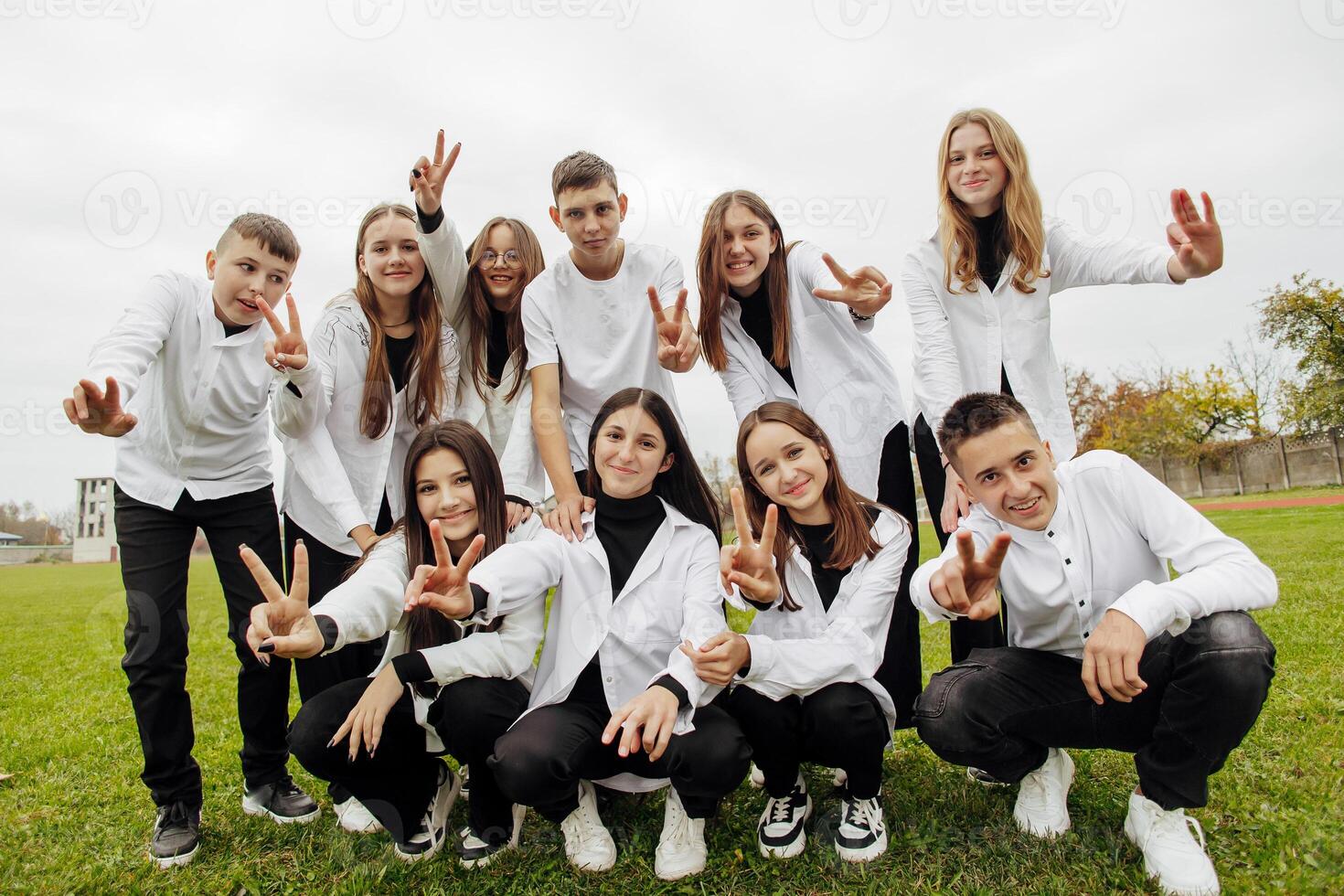 A group of many happy teenagers dressed in the same outfit having fun and posing in a stadium near a college. Concept of friendship, moments of happiness. School friendship photo