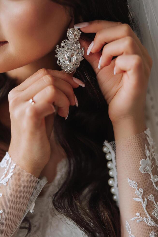 de cerca de un hermosa niña en suave satín ropa interior vistiendo pendientes. Boda Mañana de el novia. publicidad decoraciones un mujer va en un fecha. foto