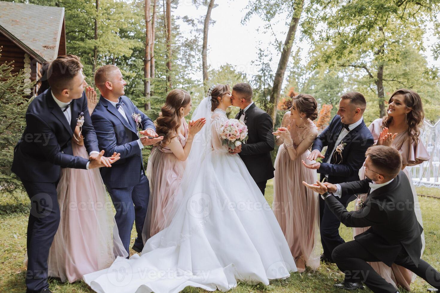 full-length portrait of the newlyweds and their friends at the wedding. The bride and groom with bridesmaids and friends of the groom are having fun and rejoicing at the wedding. photo