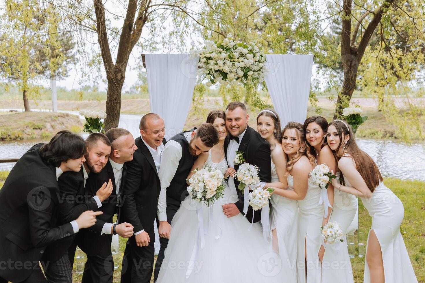 full-length portrait of the newlyweds and their friends at the wedding. The bride and groom with bridesmaids and friends of the groom are having fun and rejoicing at the wedding. photo
