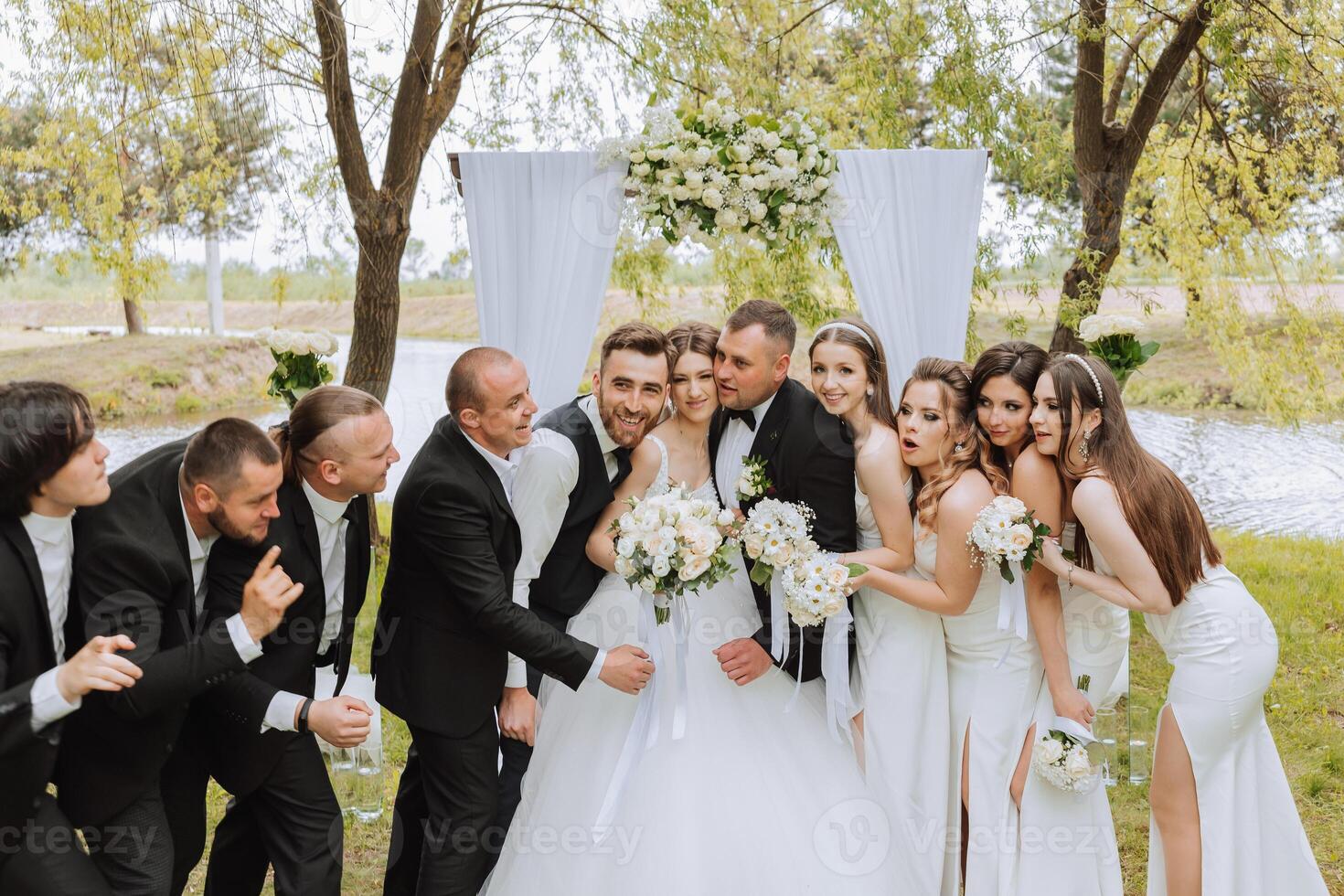 full-length portrait of the newlyweds and their friends at the wedding. The bride and groom with bridesmaids and friends of the groom are having fun and rejoicing at the wedding. photo