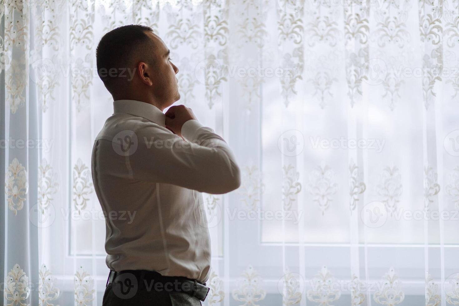A man poses and fastens a black jacket. Portrait of the groom. Fashion and style. Business photo