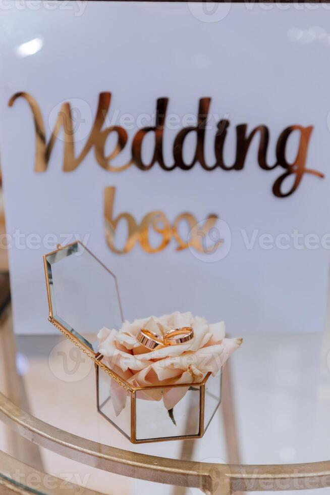 gold wedding rings on a rose flower in a glass box. The concept of event agencies for the ceremony of the bride and groom. photo