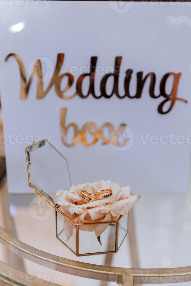 gold wedding rings on a rose flower in a glass box. The concept of event agencies for the ceremony of the bride and groom. photo