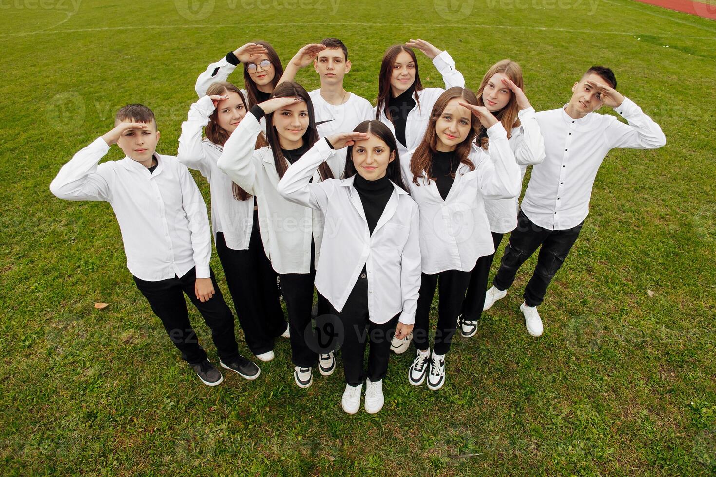 A group of many happy teenagers dressed in the same outfit having fun and posing in a stadium near a college. Concept of friendship, moments of happiness. School friendship photo