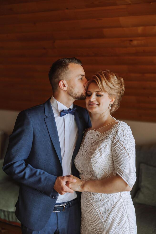 mother helps her adult son prepare for the wedding ceremony. An emotional and touching moment at a wedding. A mother hugs her son photo