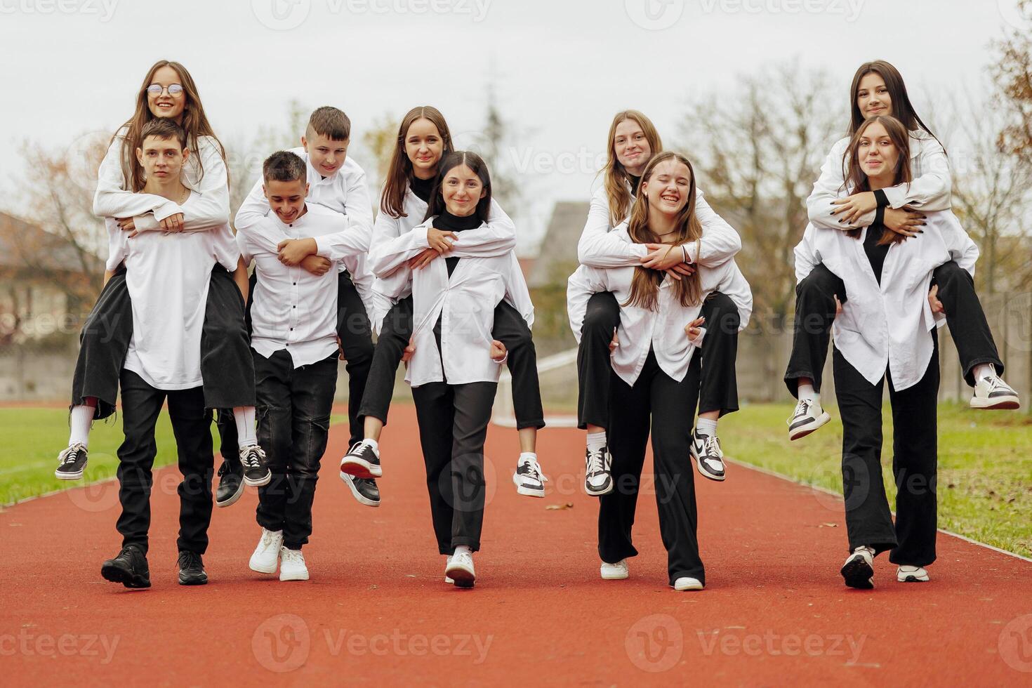 A group of many happy teenagers dressed in the same outfit having fun and posing in a stadium near a college. Concept of friendship, moments of happiness. School friendship photo