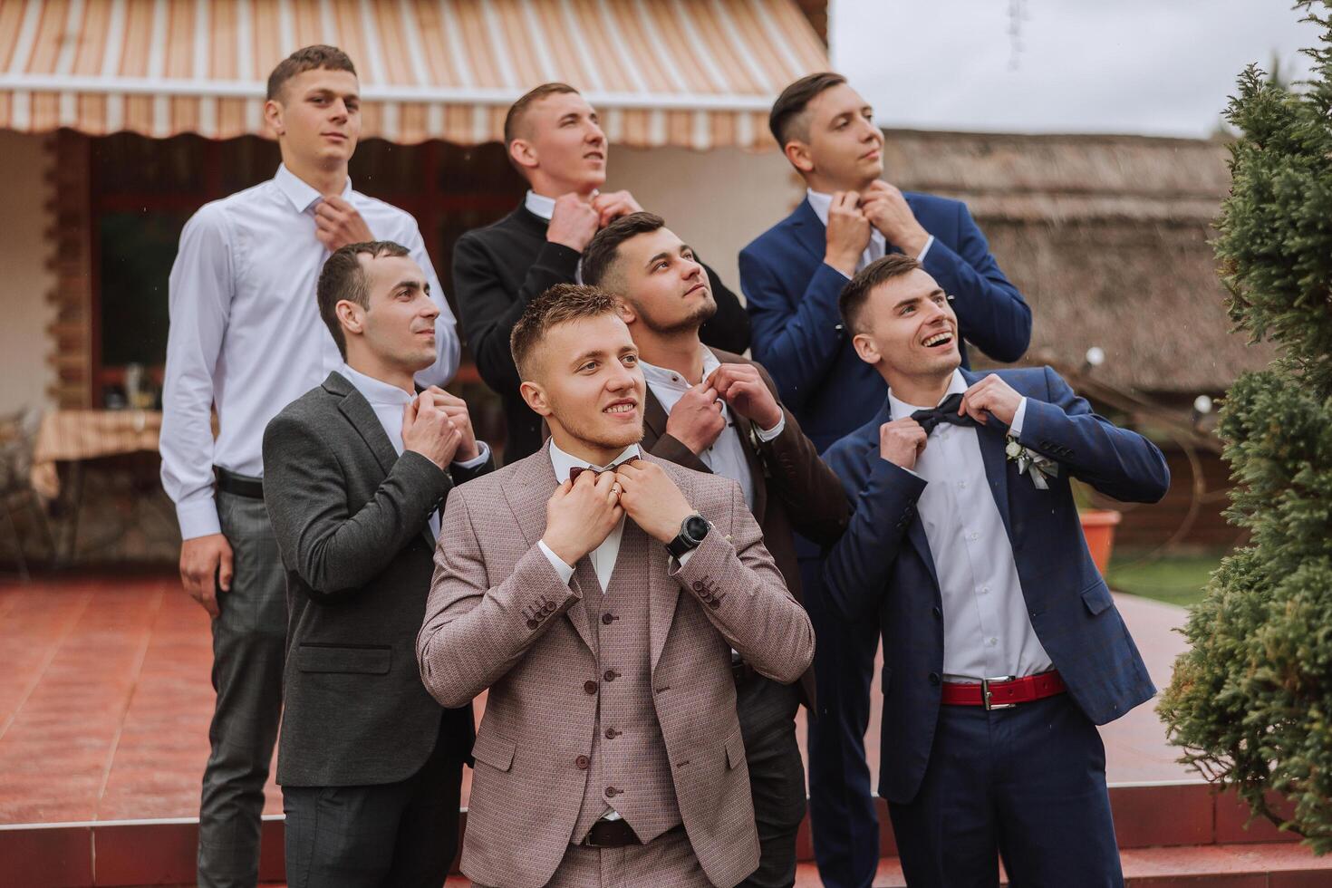Cheerful, young, energetic witnesses of the groom next to the groom. Friends congratulate the groom. Groom and his funny friends having fun on the wedding day of the newlyweds. photo