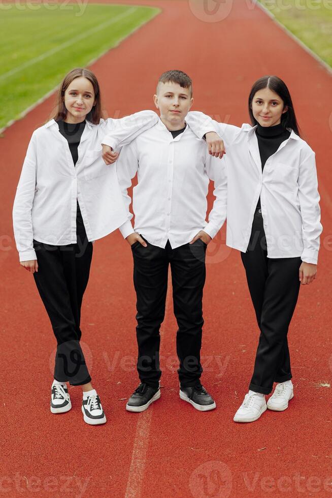 retrato de Tres Adolescente en casual ropa sentado en un estadio y posando mirando a el cámara. concepto de amistad. un momento de felicidad. foto