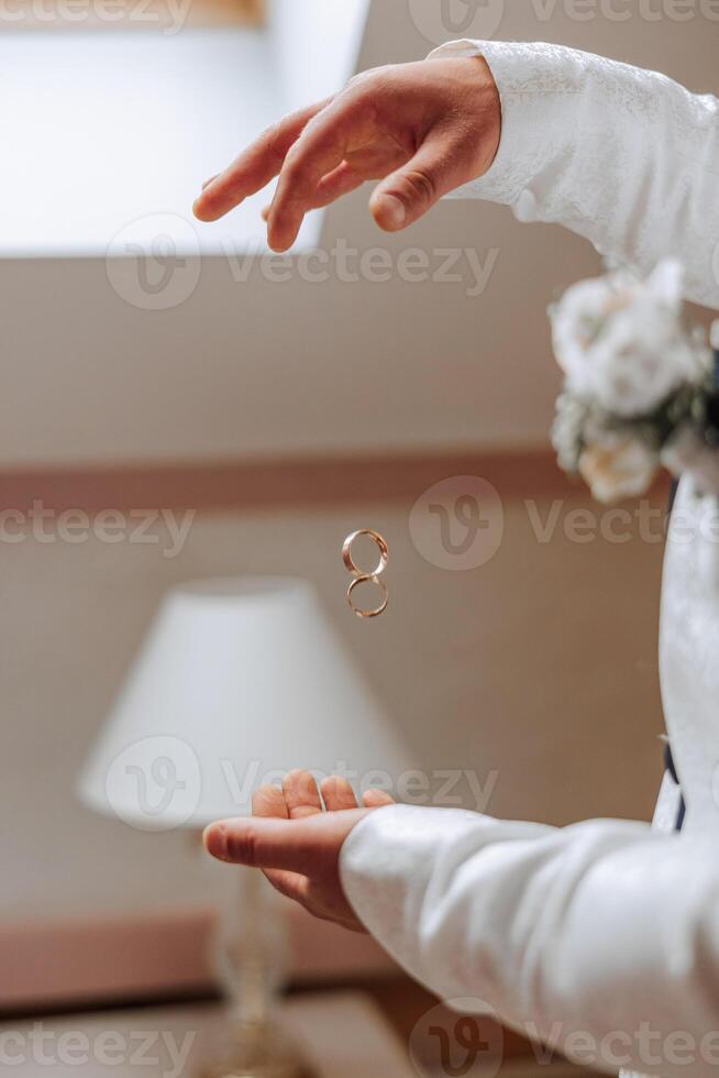 Playful excited young groom throwing wedding ring. Closeup photo of hands throwing wedding