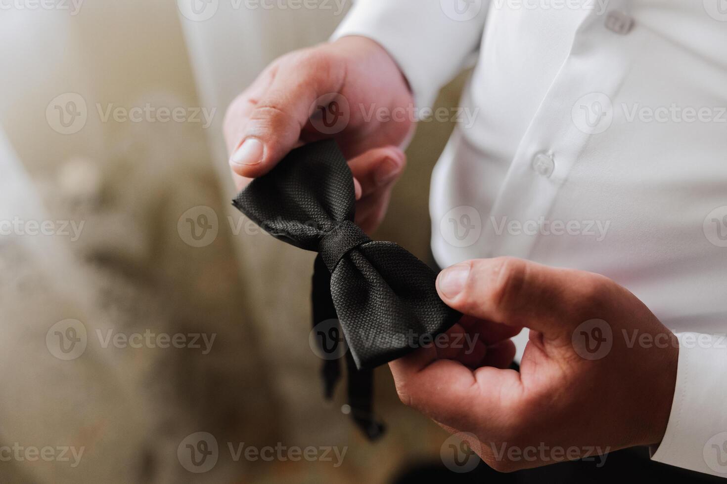 man's tie in hands, close-up photo of hands. The groom is preparing for the ceremony. Last preparations.