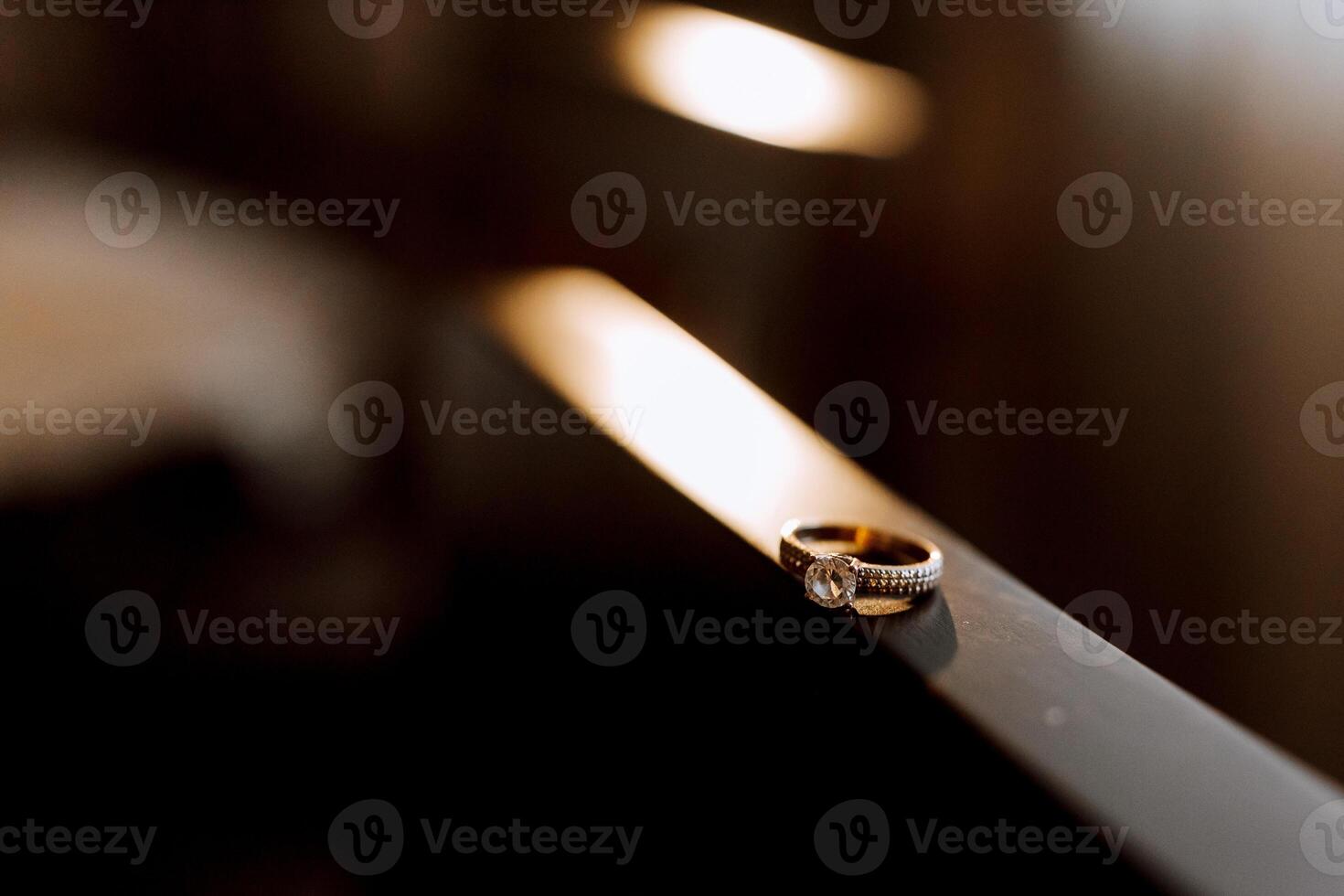 Gold wedding ring with a diamond on a brown background, focus on the wedding ring. blurred background photo