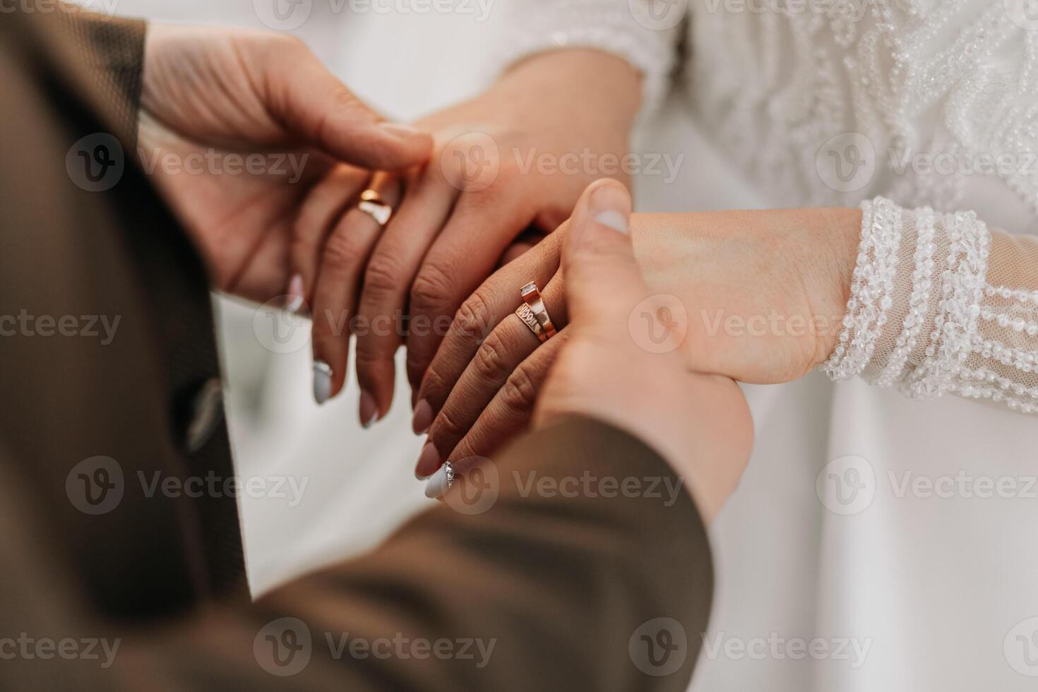 Cropped photo of the bride and groom holding hands. Emphasis on hands.