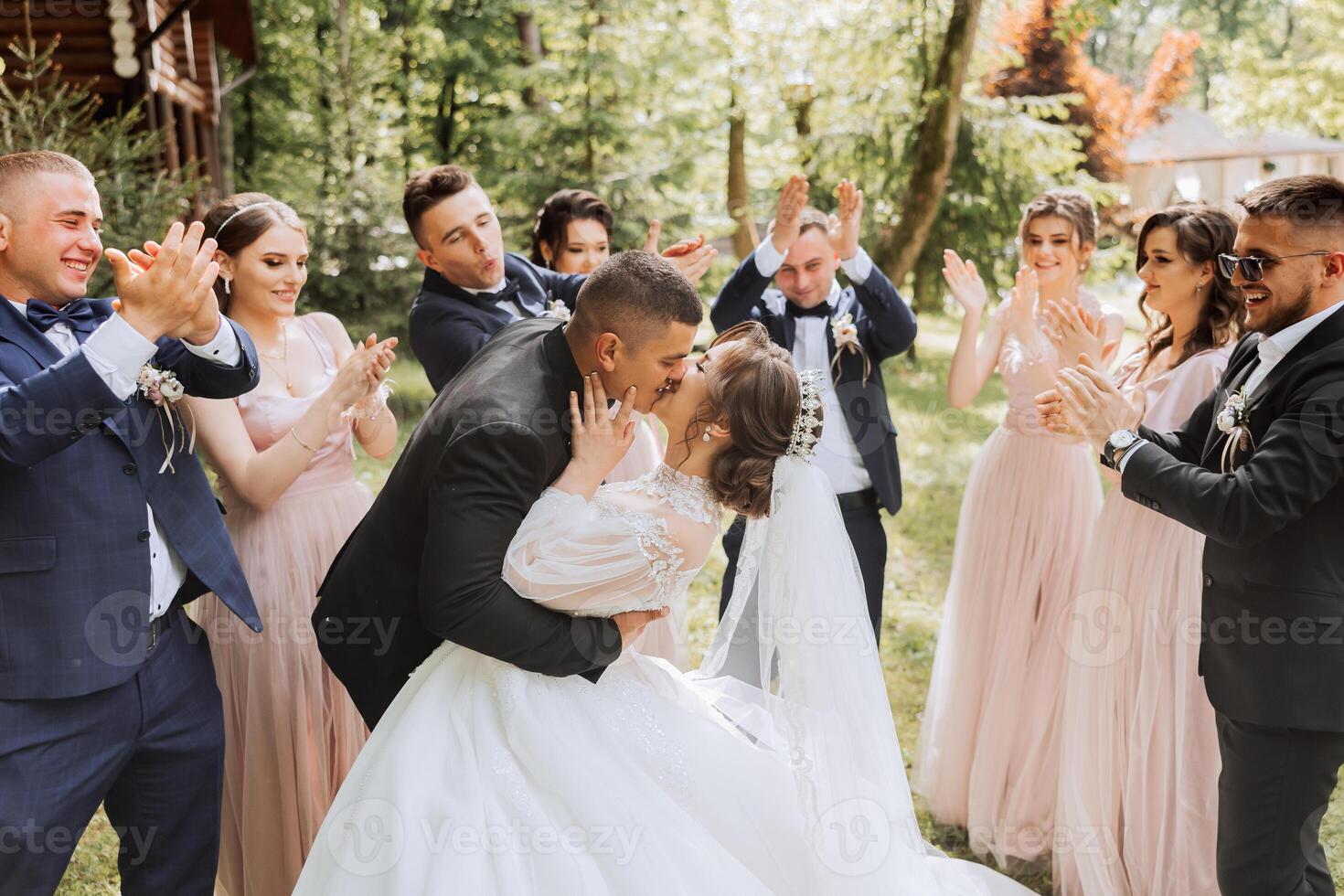 full-length portrait of the newlyweds and their friends at the wedding. The bride and groom with bridesmaids and friends of the groom are having fun and rejoicing at the wedding. photo