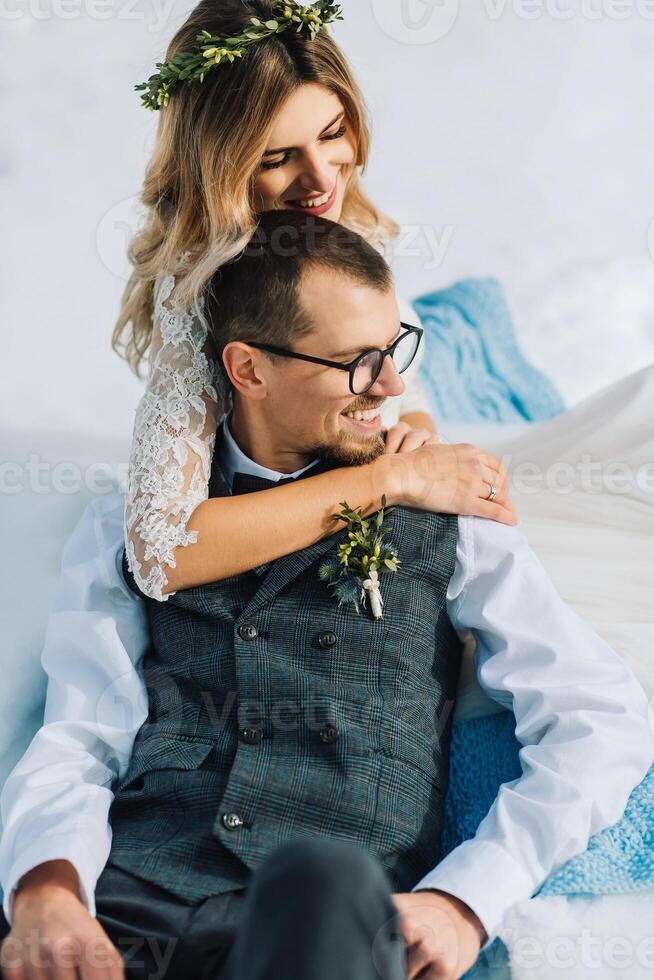 young man and woman running lying on snow, laughing, fooling around, having fun playing snowballs. European winter wedding. Portrait of the bride and groom in the snow photo