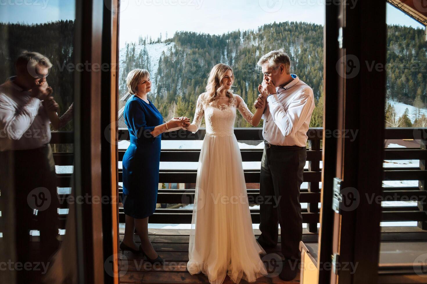 Happy parents help and rejoice for their soon-to-be-married daughter. Touching moments at the wedding. Mom gently holds her daughter's hand, dad gently kisses the bride's hand photo