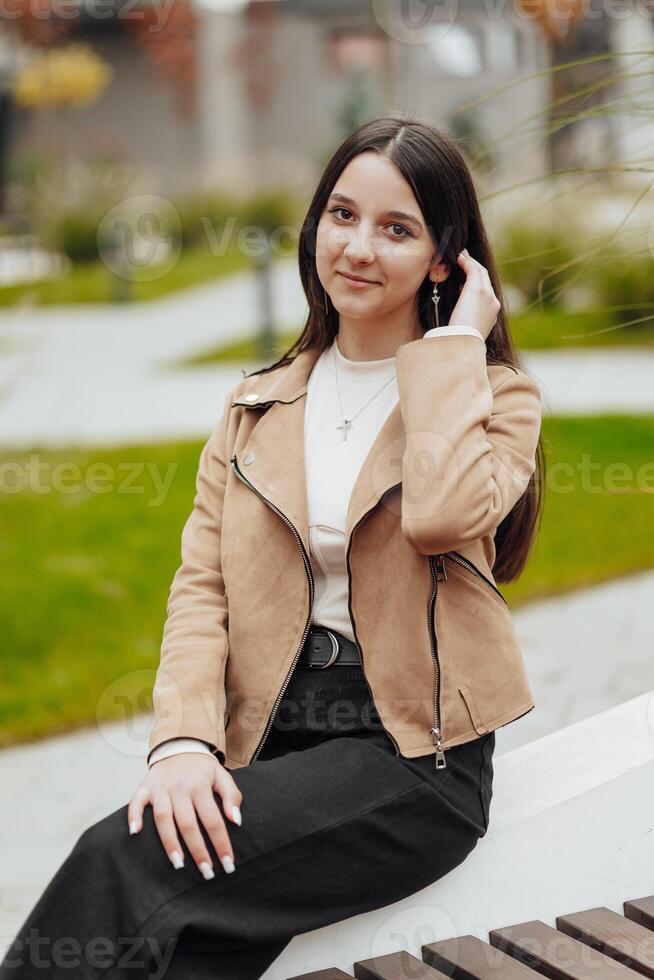 Vertical photo. Beautiful carefree young teenage girl in casual clothes. Portrait of a beautiful girl against the background of nature with a blurred background. photo