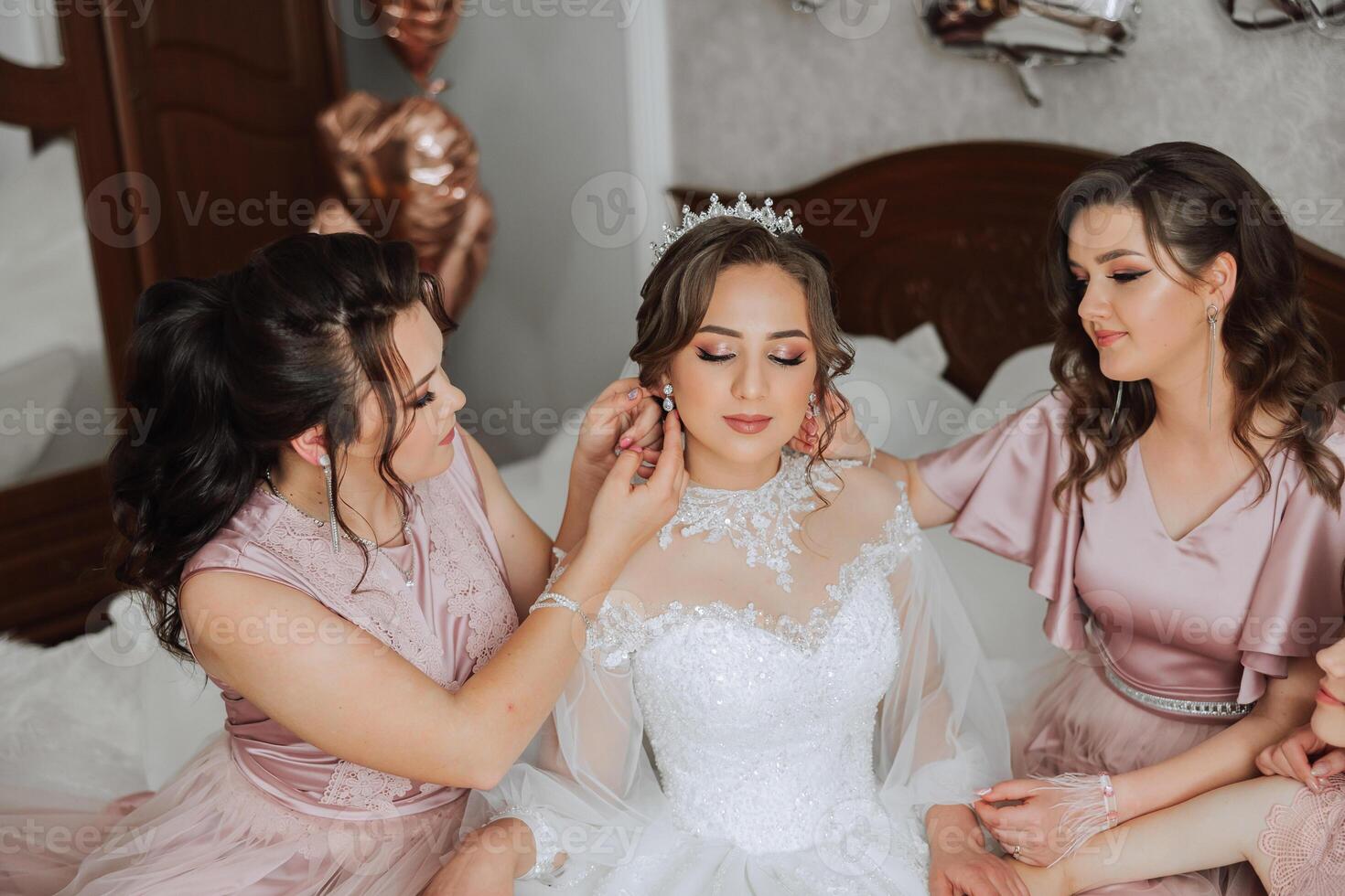Friends rejoice with the bride in the morning. They take pictures, smile, help the bride fasten her dress. photo