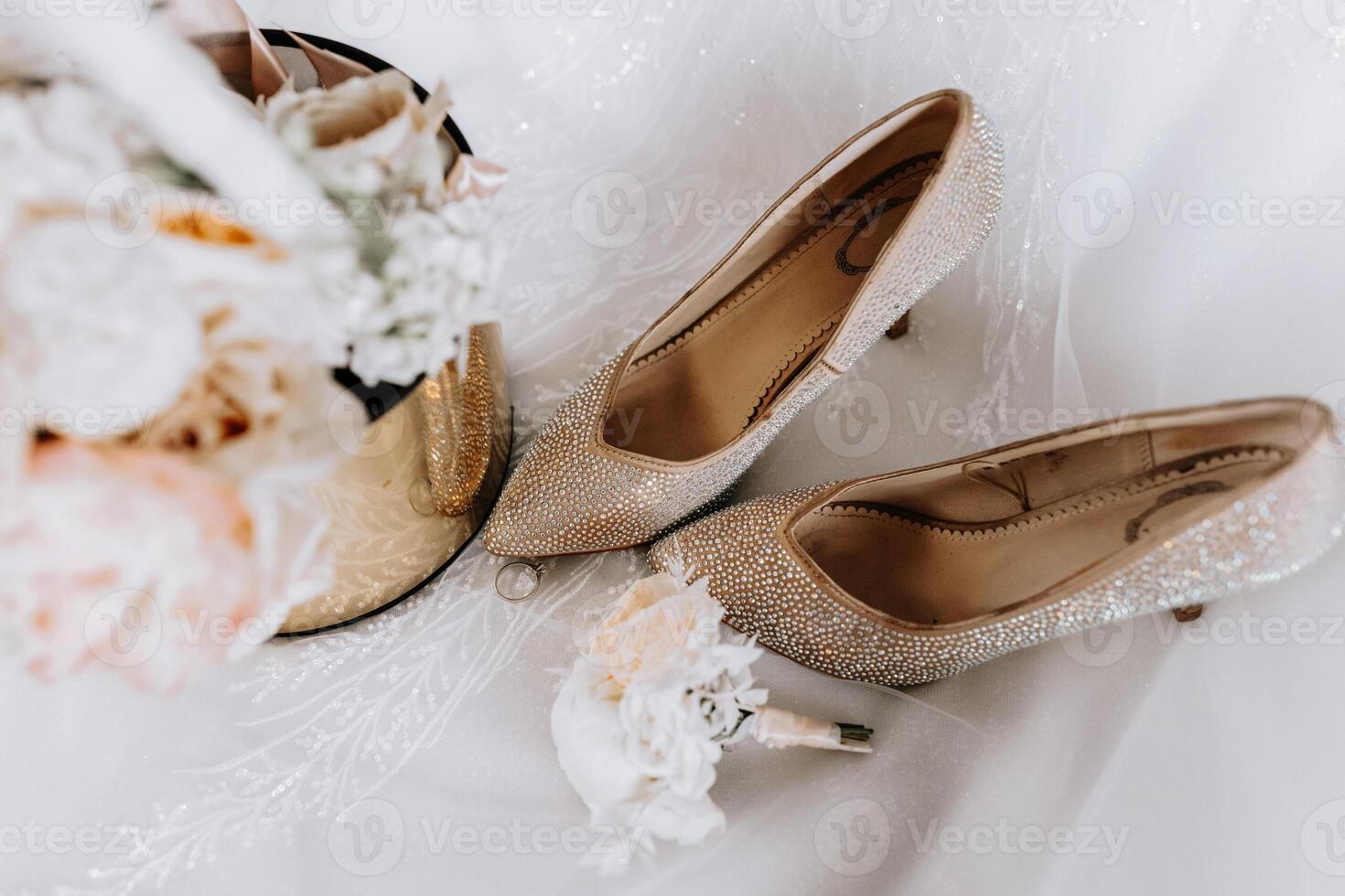 The bride's engagement ring, fashionable stilettos, fresh rose flowers. Wedding details in golden style. photo