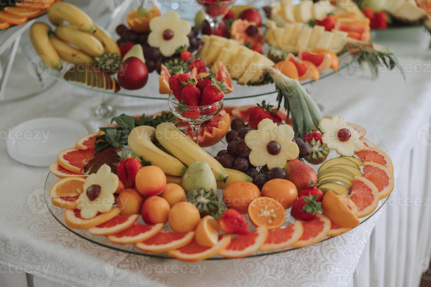 A banquet table full of fruits and berries, an assortment of sweets. Bananas, grapes, pineapples. Fruit compositions for the holiday. photo