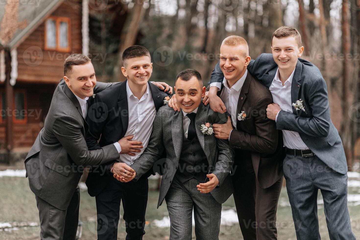 The groom and his friends are dressed in suits, fooling around in nature during a photo shoot. A group of men. Wedding in nature