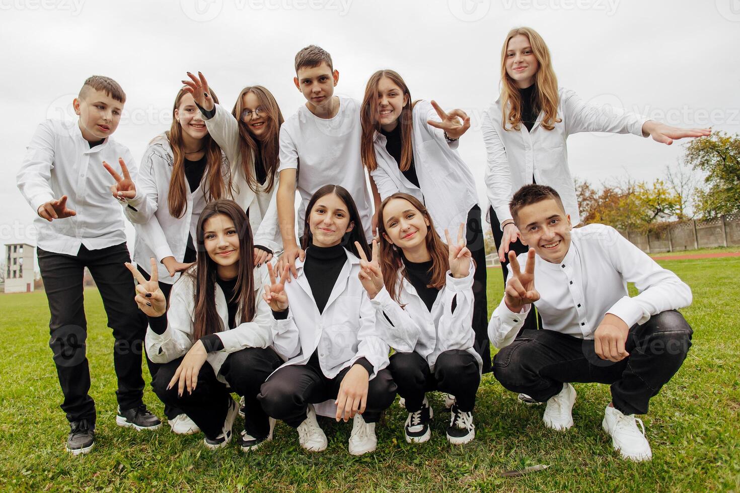 A group of many happy teenagers dressed in the same outfit having fun and posing in a stadium near a college. Concept of friendship, moments of happiness. School friendship photo