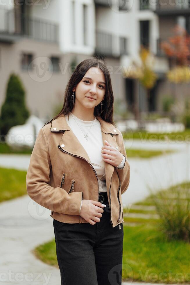 Vertical photo. Beautiful carefree young teenage girl in casual clothes. Portrait of a beautiful girl against the background of nature with a blurred background. photo