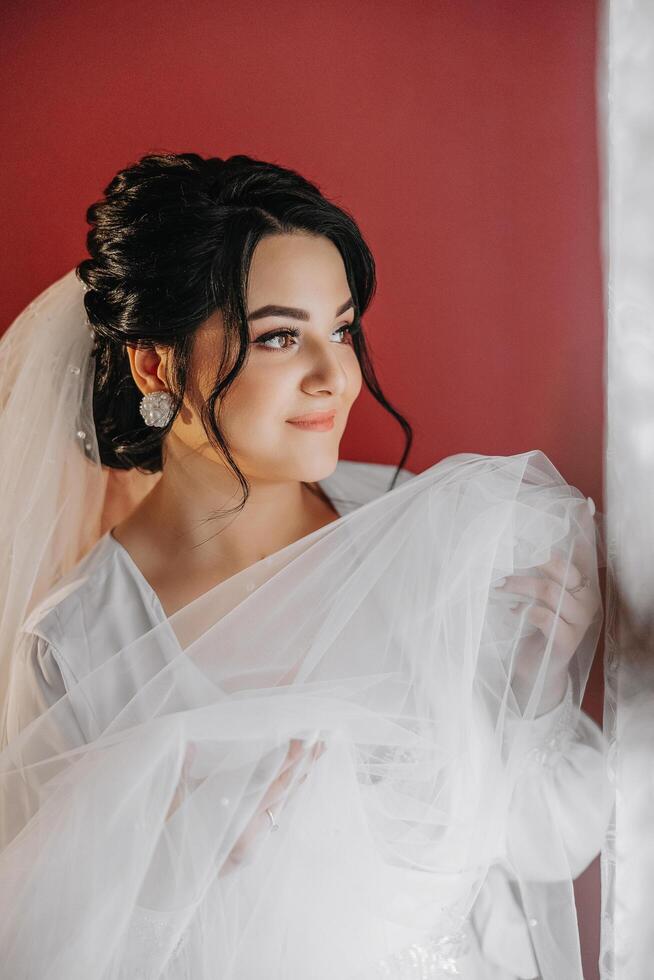 A beautiful brunette bride with a tiara in her hair is getting ready for the wedding in a beautiful robe in boudoir style. Close-up wedding portrait, photo. photo