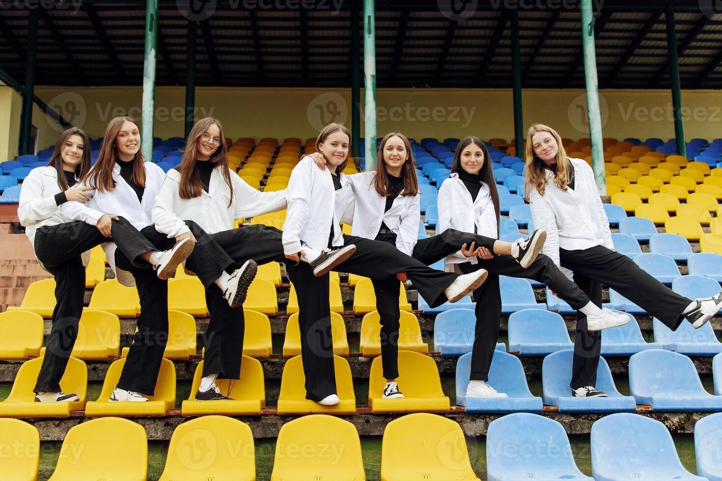 un grupo de muchos contento adolescentes vestido en el mismo atuendo teniendo divertido y posando en un estadio cerca un colega. concepto de amistad, momentos de felicidad. colegio amistad foto