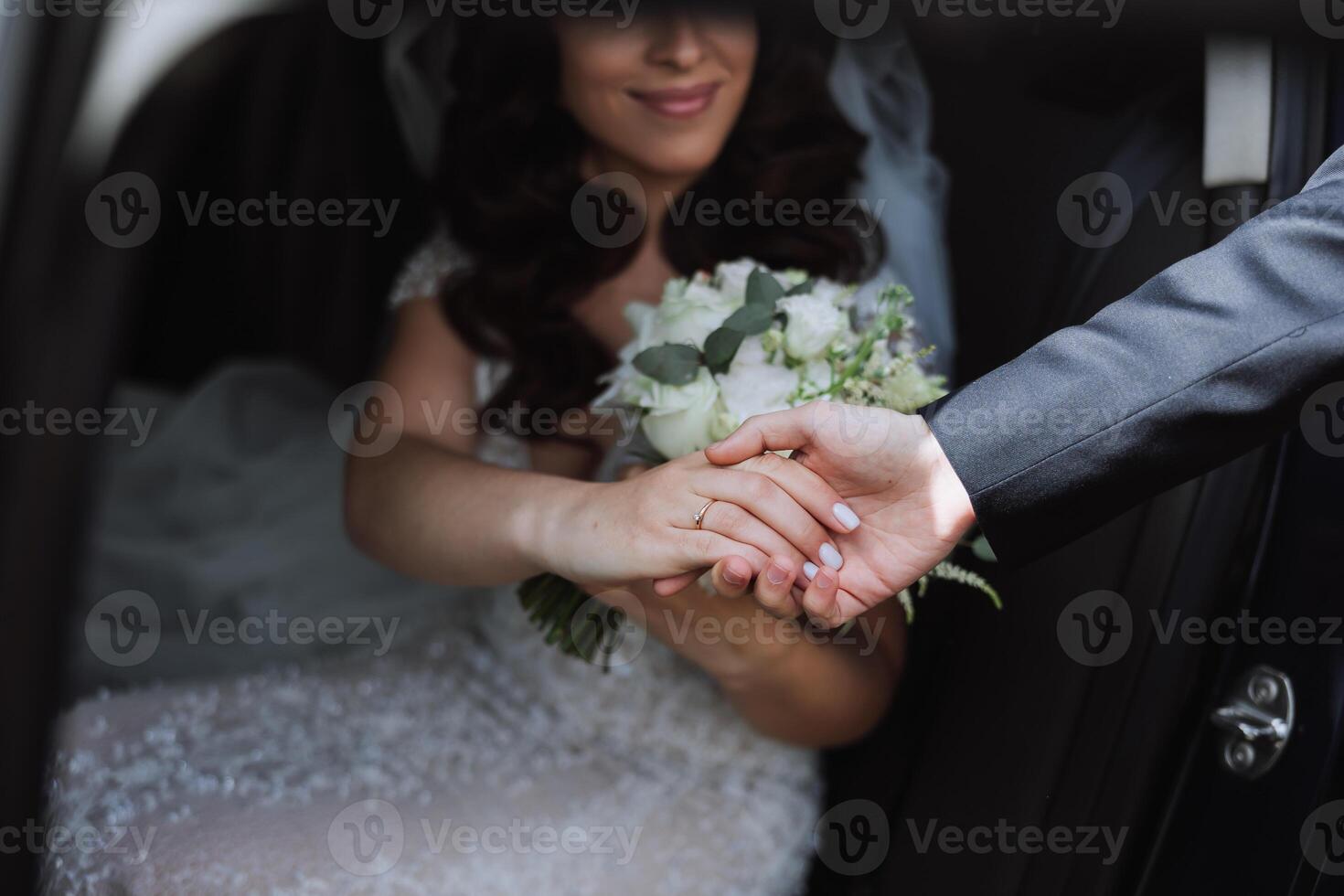 un hermosa novia, sentado en un auto, da su mano a su marido. un hermosa novia con un ramo de flores de flores en su manos es sentado en un elegante costoso coche. foto