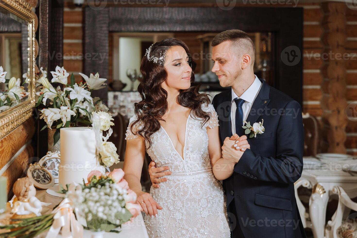 Wedding. Groom and bride near the wedding cake. A sweet and delicious dessert for a wedding. The bride cuts the wedding cake with the help of her lover. The groom embraces his beloved. photo