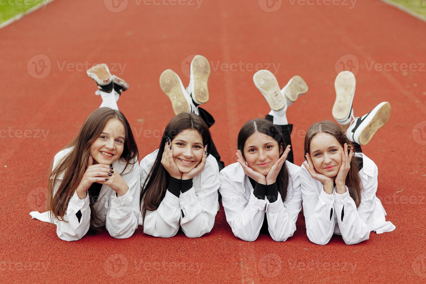 Portrait of two teenage girls in casual clothes sitting in a stadium and posing looking at the camera. Concept of friendship. A moment of happiness. photo