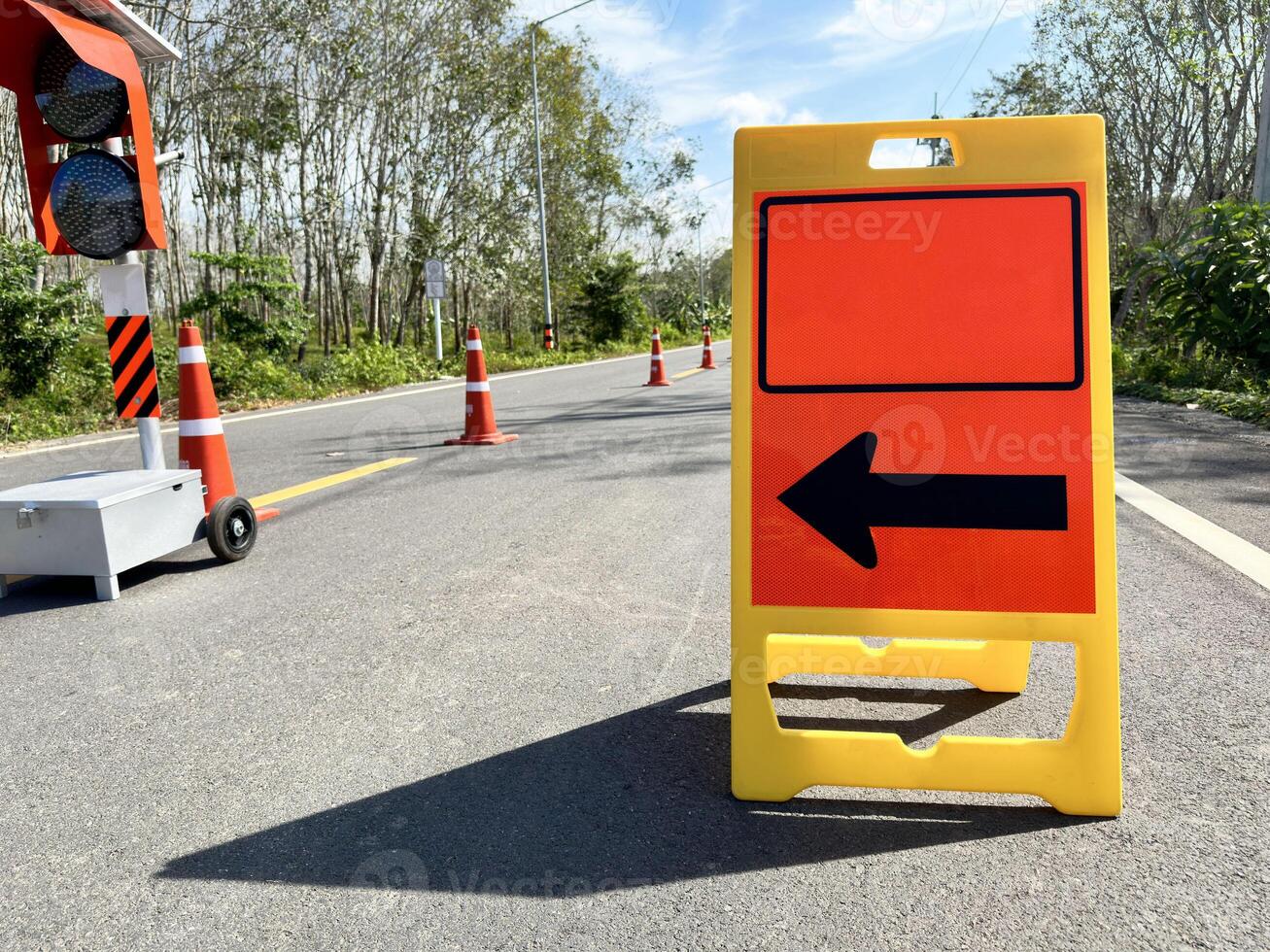 Floor-mounted folding signs warning the road to follow the black arrows for safety on the road. photo