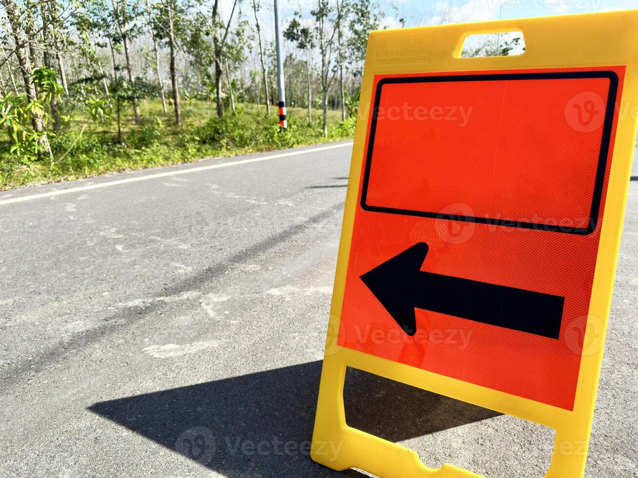 Floor-mounted folding signs warning the road to follow the black arrows for safety on the road. photo